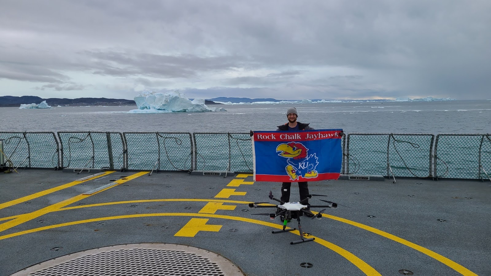 Alex Zugazagoitia holds a KU flag while aboard the Danish Navy vessel in Greenland