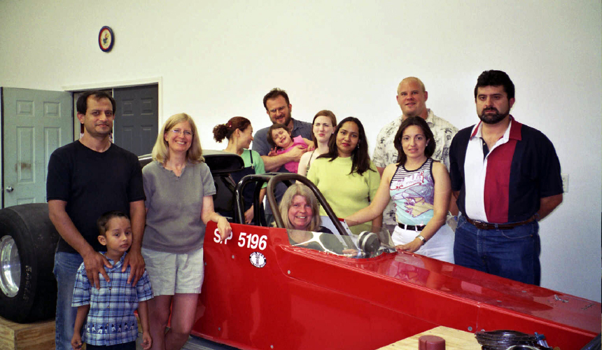 Kristin Bowman-James sits in her red race car, Reddy, surrounded by her chemistry lab group.
