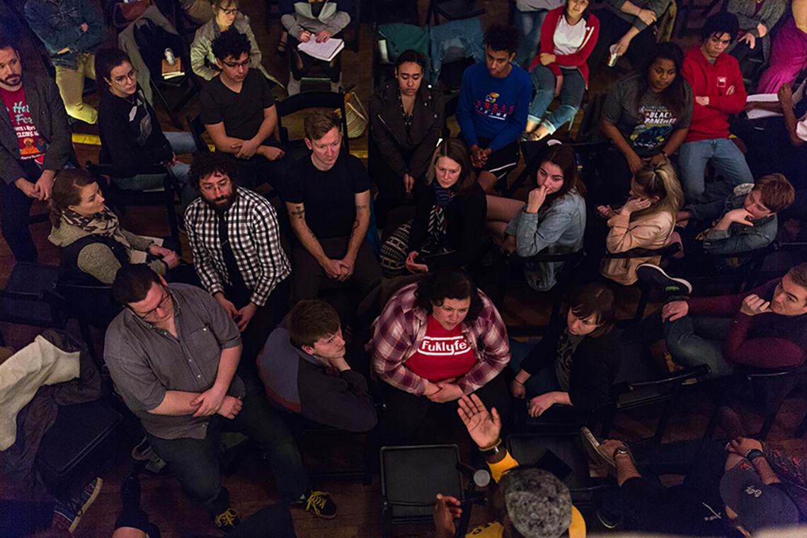 A bird's eye view shows a speaker talking in the middle of a crowd to talk more closely to them